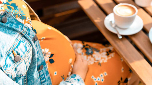 Pregnant woman holds coffee and phone